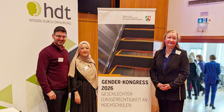 Gruppenfoto: Panourgias Papaioannou, Sude Pekşen und Prof. Liudvika Leišytė stehen neben einem Plakat des Gender-Kongresses 2026